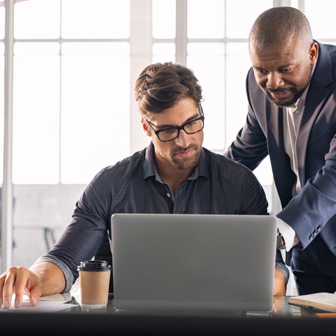 Business multiethnic colleagues having meeting in modern office. Smart business partners planning work together. Young businessman with boss working together on laptop.